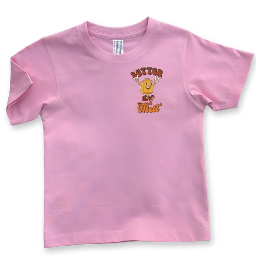 Front view of pink kids' t-shirt with small chest design of a cheerful butter character and the words "Butter Wouldn't Melt" in orange and brown hues