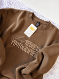 Personalized embroidered sweatshirt in walnut color with stylish text design and tag on a white background.