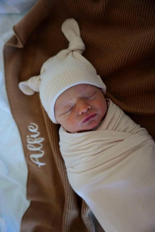 Baby wrapped in soft custom embroidered baby blanket with personalized name, snuggled in warmth and comfort.