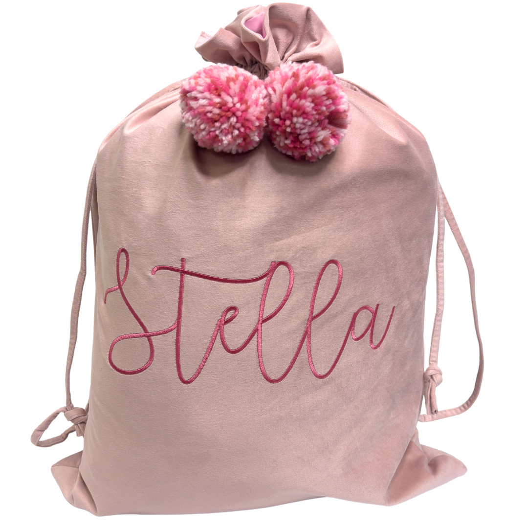 Personalised pink velvet Santa sack with rose pink embroidered name ‘Stella’ and matching pastel pink pom poms.